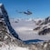 A helicopter flying over the snowy peaks of a mountainous snow covered valley